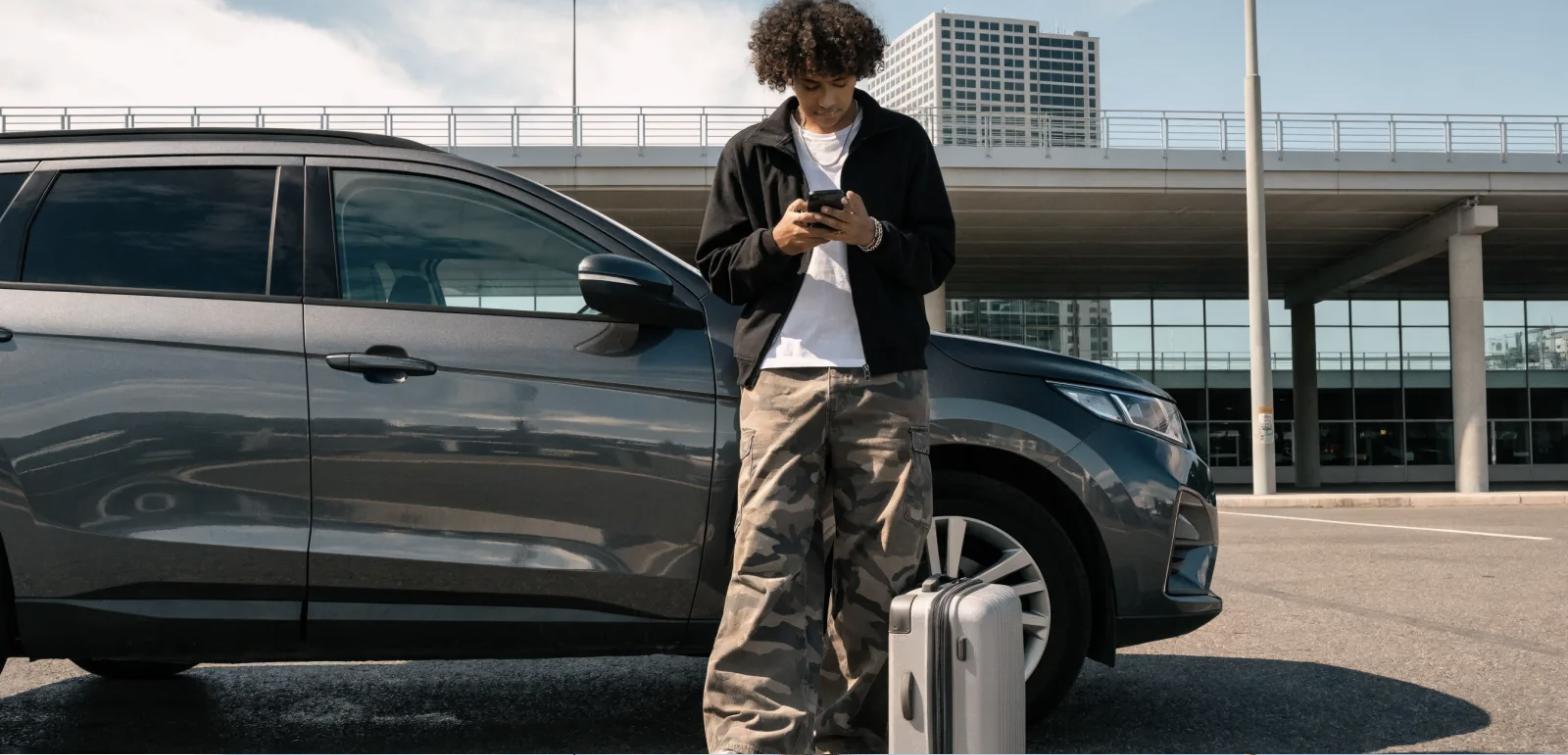 pessoa comparando preço de estacionamento de aeroporto pelo celular ao lado do carro